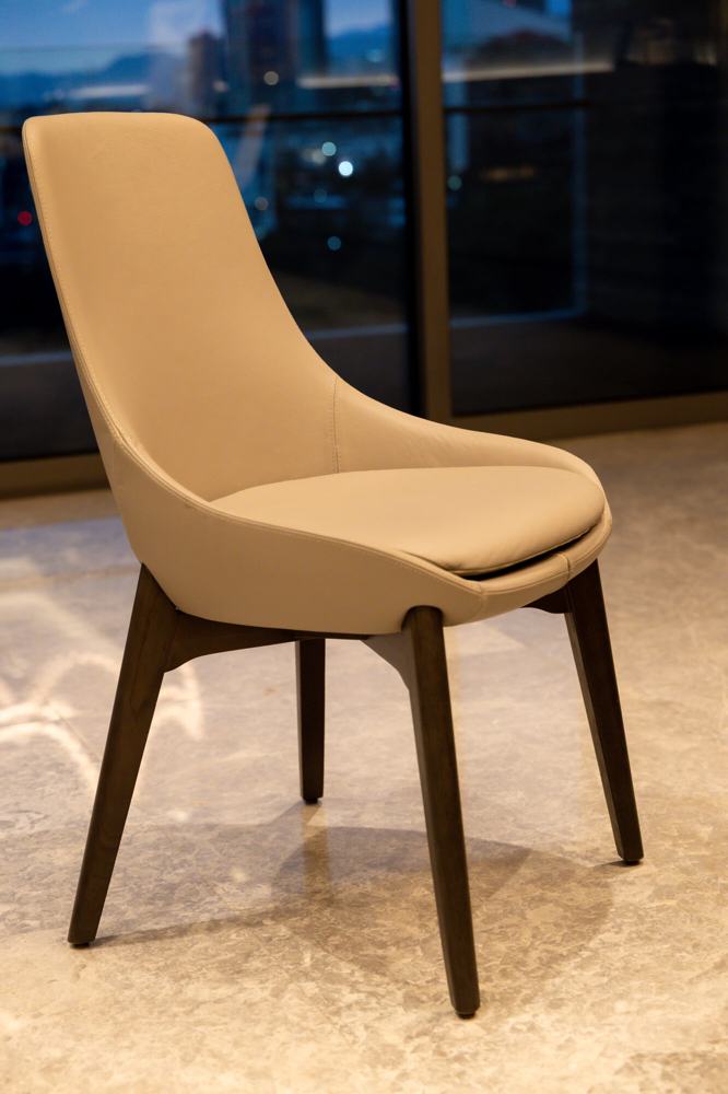 Silla tapizada en piel con patas de madera oscura