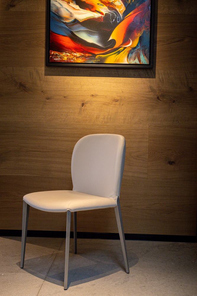 Silla tapizada bajo una pintura sobre muro de madera